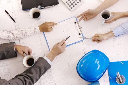 Businessmeeting, closeup hands of architects pointing at clipboard on office table.