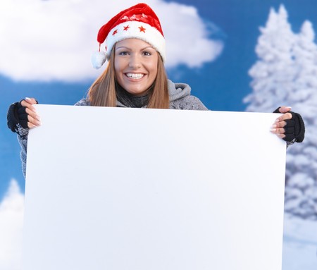 Attractive young woman in santa hat holding huge blank letter front of herself, smiling.の写真素材