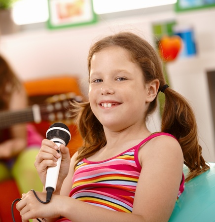 Closeup portrait of happy schoolgirl with microphone, smiling at camera.の写真素材