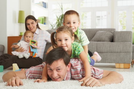 Happy family having fun posing for camera on floor of in living room at home, looking at camera, smiling.の写真素材