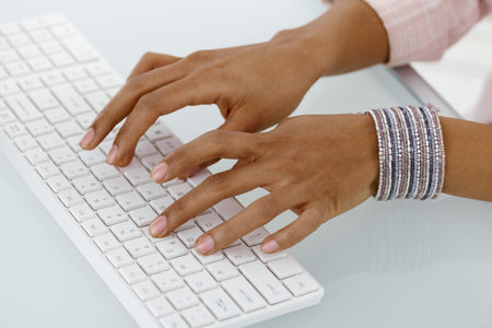 Hands of ethnic businesswoman typing on desktop keyboard. 