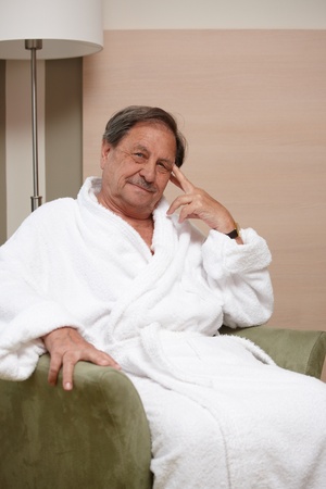 Happy elderly man sitting in armchair, looking at camera.の写真素材