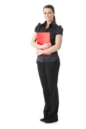 Businesswoman standing with folder handheld, smiling at camera, cutout on white.の写真素材