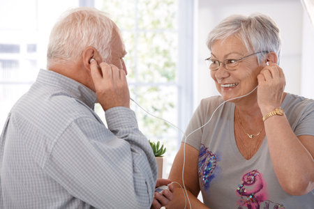 Elderly couple listening to music on mp3 player, smiling.の写真素材