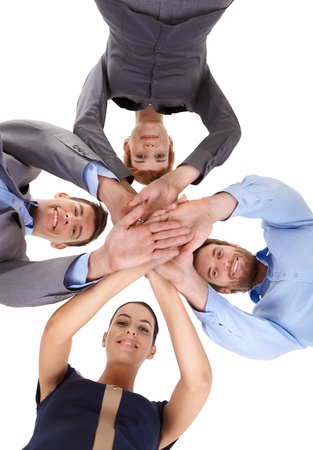 Young businesspeople putting hands together, smiling, looking at camera, view from below.の写真素材
