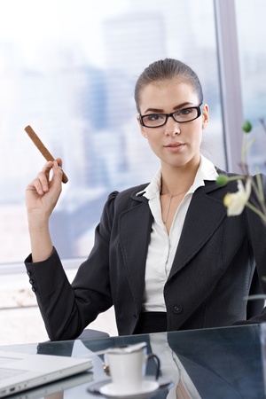 Confident smart businesswoman posing at skyscraper office with cigar handheld.の写真素材