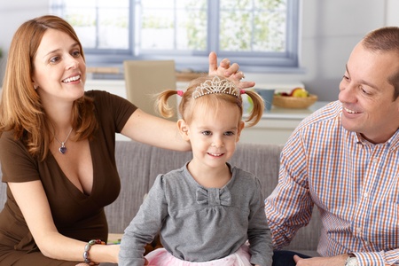 Little princess in tiara smiling, pregnant mother and father adoring.の写真素材