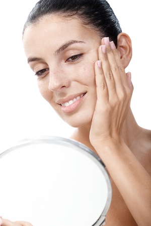 Young smiling woman looking at her face in mirror satisfied. Young smiling woman looking at her face in mirror satisfied.