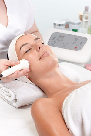Young woman getting skin rejuvenating treatment in beauty saloon, laying eyes closed. 