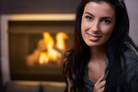 Beautiful woman smiling at home by fireplace.の写真素材