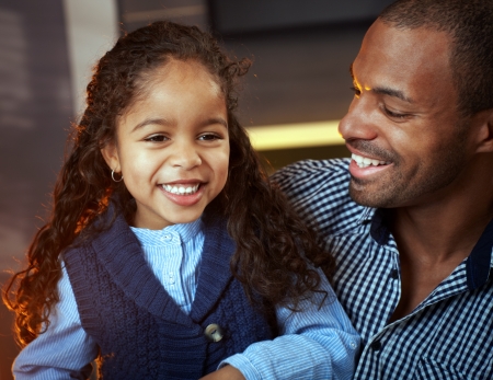 Portrait of ethnic father and cute little daughter, both smiling happily.の写真素材