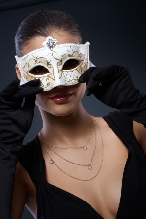 Woman in elegant black dress hiding in decorated carnival mask, seductive smile.の写真素材