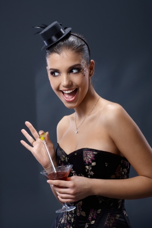 Woman in elegant dress and fancy little hat having fun, posing with cocktail.の写真素材