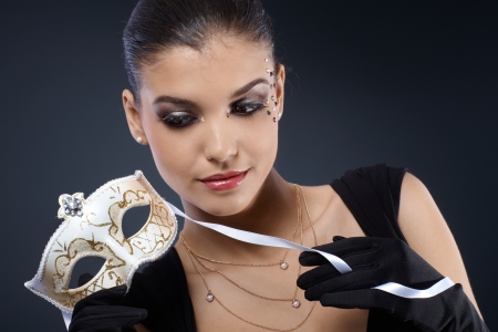 Portrait of smart woman in fancy makeup with carnival mask and gloves  
の写真素材
