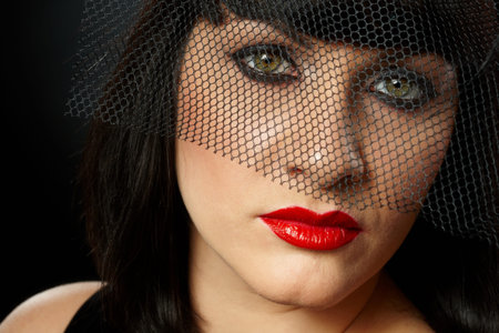 Dramatic portrait of young widow wearing elegant black clothes and in veil.