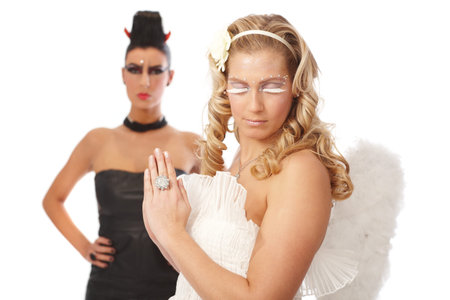 Praying angel turning head away from devil.の写真素材