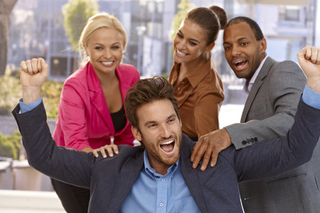 Handsome businessman celebrating success with young colleagues.