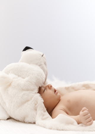 Side view of adorable sleeping infant with big bear hat on head.の写真素材