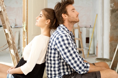 Young couple sitting on floor exhausted in renewing house  Sitting back to back   65533;の写真素材