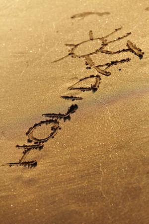 Holiday text drawn in sand on a sunny summer day.の写真素材
