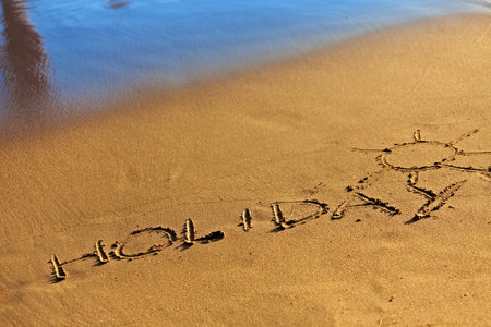 Holiday text drawn in sand on a sunny summer day.