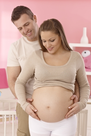Happy couple expecting a baby, hugging woman's pregnant tummy.の写真素材