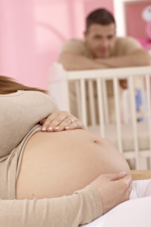 Closeup photo of naked pregnant tummy in baby's room.の写真素材