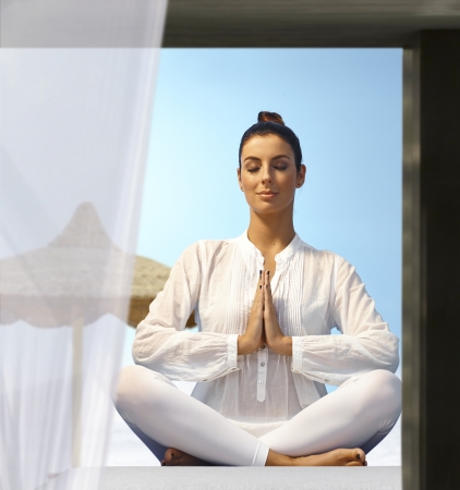 Young woman practicing yoga outdoors, sitting eyes closed in prayer position.の写真素材