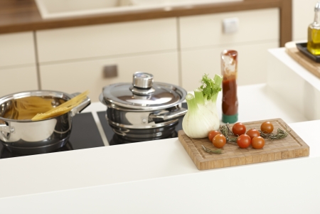 Closeup kitchen worktop with vegetables and saucepan on ceramic hob.の写真素材