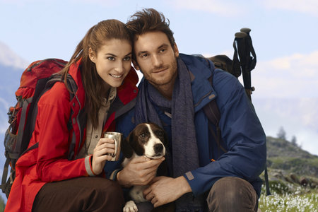 Happy hikers with dog enjoying spring in mountains.