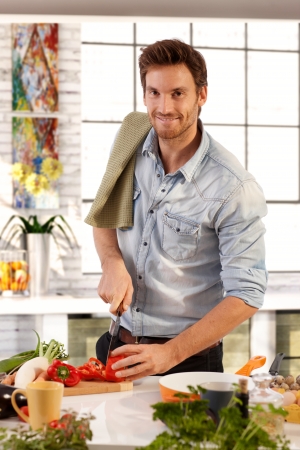 Happy caucasian man cooking in kitchen at home, smiling.の写真素材