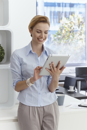 Happy young businesswoman using tablet computer, smiling.の写真素材