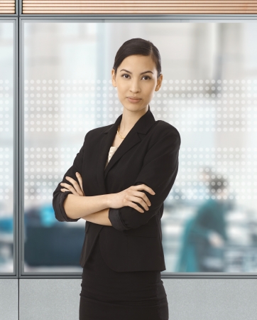 Asian businesswoman standing at glass wall in office.の写真素材
