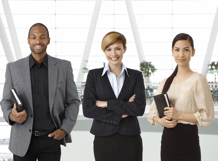 Interracial team of businesspeople standing for portrait in business hallway, smiling.の写真素材
