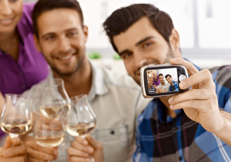 Young man making self portrait of his friends by digital camera.の写真素材