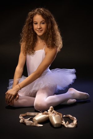 Pretty ballet student sitting on floor, smiling, looking at camera.の写真素材