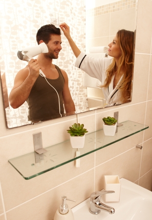 Young couple getting ready in the morning in the bathroom, drying hair.の写真素材