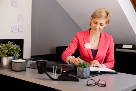 Young businesswoman sitting at desk, working in office.の写真素材