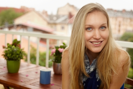 Closeup portrait of happy young woman at balcony, looking at camera.の写真素材