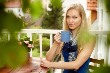 Portrait of young nordic woman sitting at balcony, drinking tea, looking away.の写真素材
