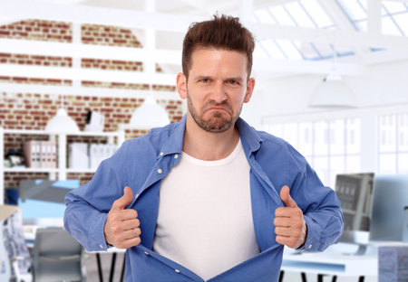 Aggressive man tearing shirt apart on his chest, looking wild.の写真素材