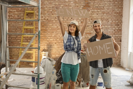 Young couple holding new home text at renovation site.の写真素材