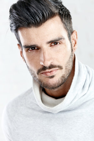 Portrait photo of cool handsome young man looking at camera, white background.