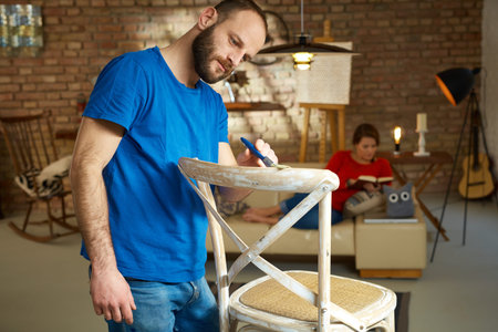Man renewing chair at home, painting wooden surface.の写真素材