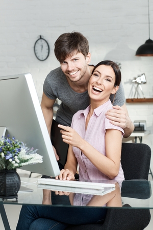 Portrait of happy young loving couple using computer, laughing happy.の写真素材