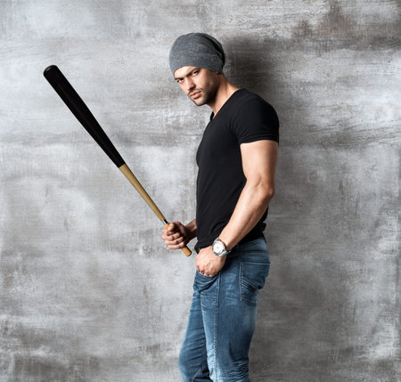 Bad guy standing at concrete wall holding hammer.