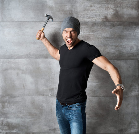 Bad guy standing at concrete wall holding hammer.の写真素材