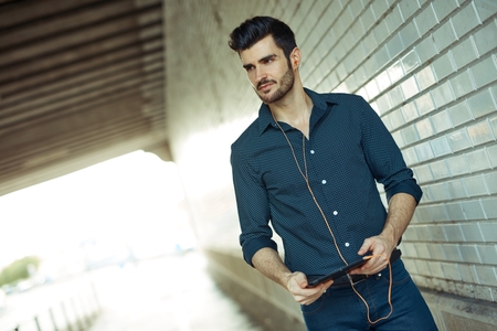 Handsome young man walking in underpass, using tablet computer.の写真素材