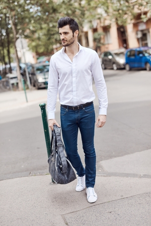 Casual young man walking on the street, looking away.の写真素材