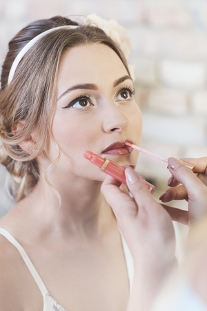 Makeup artist applying lipstick on bride lips.の写真素材